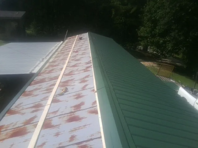 Old rusted panels beside newly installed green metal roofing — Wind Damage Roof Repair by Roofing Brothers in Pine Mountain Valley