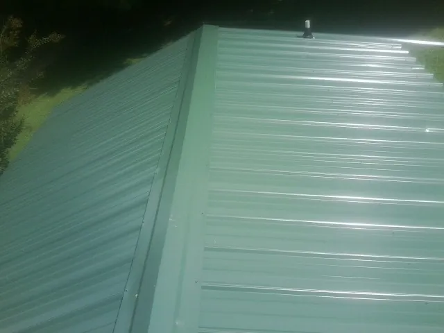 New green metal panels meeting at the ridge of a roof — Flat Roof Repair work by our crew in Pine Mountain Valley