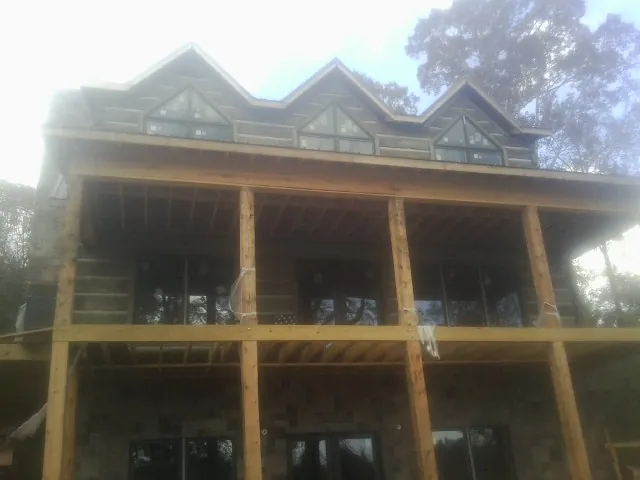 Dormers and porch framing on a large log home under construction — Roof Coating work by our crew in Pine Mountain Valley