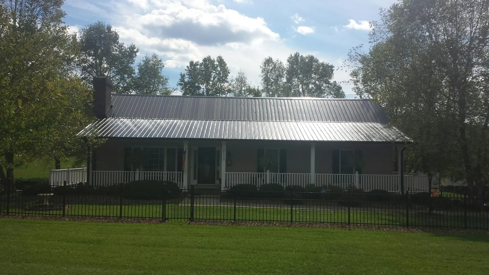 Gray metal roof on a brick ranch with a full width front porch — Gutter Guard Installation work by our crew in Pine Mountain Valley