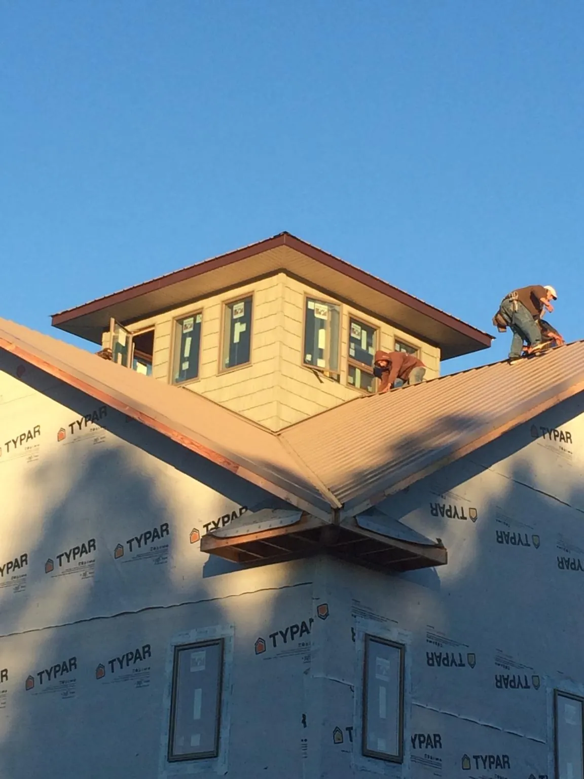 Roofers working around a rooftop cupola on a new metal roof at sunset — Roof Waterproofing in Pine Mountain Valley by Roofing Brothers